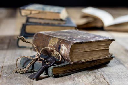Very old book and key on an old wooden table. Old room, wooden table and book with key, black backgroundの写真素材