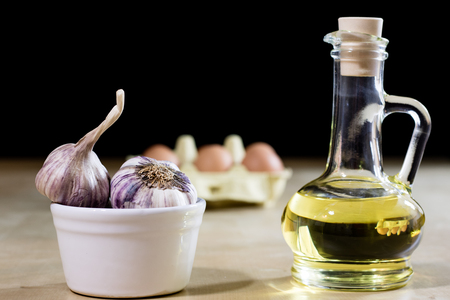 Garlic, eggs and oil on a wooden kitchen table. Kitchen with products for food preparation. Black backgroundの写真素材