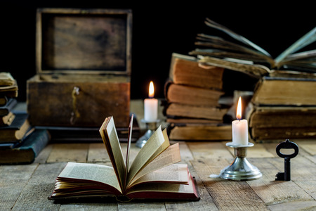 Old books and candles on a wooden table. Old room, reading room. Black backgroundの写真素材