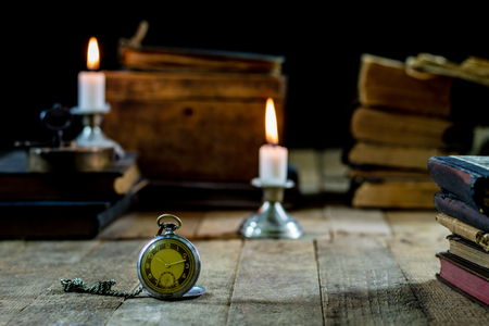 Old books and candles on a wooden table. Old room, reading room. Black backgroundの写真素材