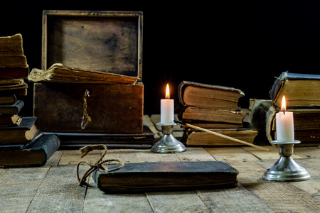 Old books and candles on a wooden table. Old room, reading room. Black backgroundの写真素材