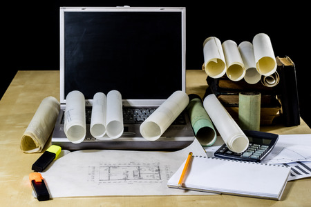 architect's table, laptop, calculator on the table. Plans, projects and notepad on the architect's...