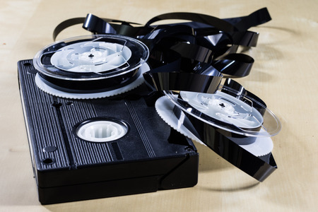 Image on video tape. Videotape tape wound on spools. Wooden table, black background.の写真素材