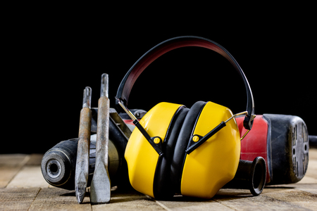 Safety accessories and impact hammer. Accessories for a builder on a wooden table. Black background.の写真素材