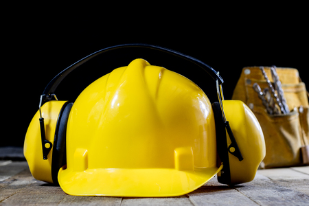 Protective clothing, helmet, gloves and glasses. Hearing protectors. Safety accessories on a wooden table. Black background.の写真素材