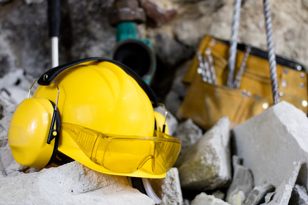 Demolition of walls. Electric hammer helmet and hearing protection lying on the rubble. Old brick and remodeled building wall. Grunt on the background of the old wall.の写真素材