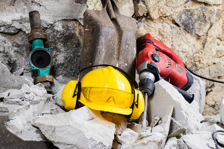 Demolition of walls. Electric hammer helmet and hearing protection lying on the rubble.の写真素材