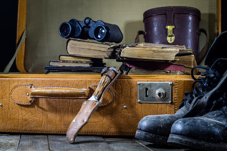 Old stylish suitcase. Old books in a suitcase. Suitcase on a wooden table. Black backgroundの写真素材