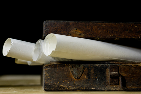 Old rolls and plans in folded paper rolls. Old book and case. Documents on an old wooden table....