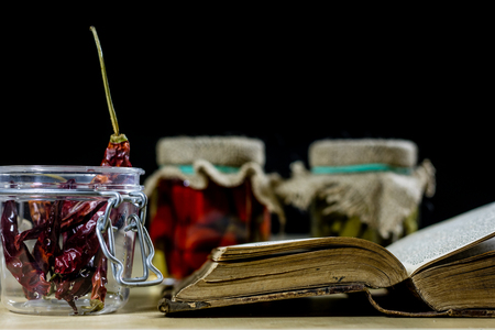 Old books and spices. Dried peppers and recipes. Old kitchen table. Black backgroundの写真素材
