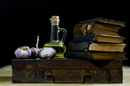Old books and spices. Dried garlic and recipes. Old kitchen table. Black backgroundの写真素材