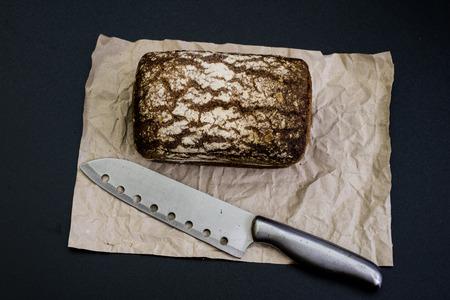 Black bread on gray paper. Spices and oil next to slices of bread. black background
