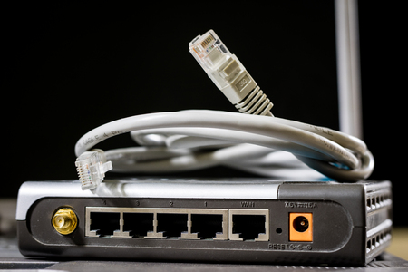 Network hub and rj45 cables on the stage. Computer accessories used in networking. Black background.