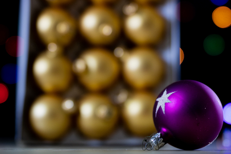 Christmas baubles in a box against a background of Christmas lights. Christmas dinner wrapped in cardboard box on the background of the lamps. Black backgroundの写真素材