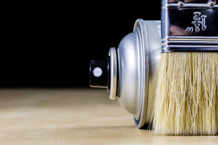 Pedzel for painting with oil paint on a wooden workshop table and a spray can. A bristle brush in a workshop. Black backgroundの写真素材