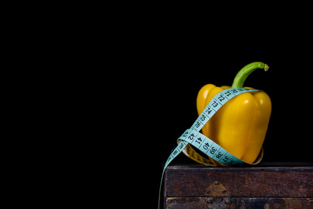 Tasty paprika on an old dark wooden table. A tailor measuring tape next to the vegetable. Vegetables...