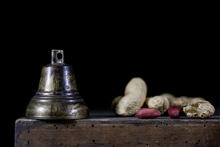 Nuts in a natural bag. A bag of nuts and a bell on an old dark wooden table. Black background