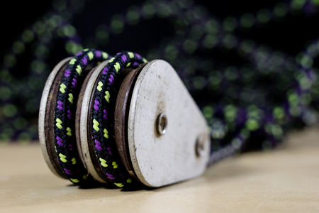 Rigging, sailing accessories. Rope block and shekel on a wooden table. Black background