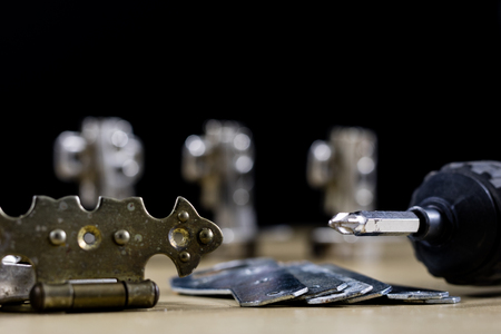 Carpentry tools and accessories on a workshop table. Hinges and screws together with the screwdriver...