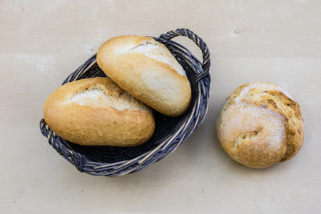 Tasty fresh bread in a wicker basket. Rolls in a basket on a wooden kitchen table. Black background.