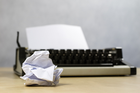 Typewriter and white card screwed into the machine. Wooden table with a typewriter. White background.の写真素材