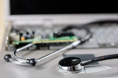 Computer treatment on a computer service. Repair and diagnostics of computer hardware. Computer equipment on a workshop table. Black background.の写真素材