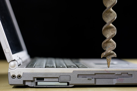 A laptop on a wooden table seen from the profile together with carpentry tools. Computer repair in a...