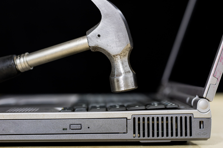 A laptop on a wooden table seen from the profile together with carpentry tools. Computer repair in a workshop. Black background.の写真素材