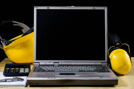 Design office and protective clothing. Wooden table and engineer's workstation. Black background.