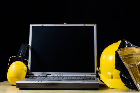 Design office and protective clothing. Wooden table and engineer's workstation. Black background.