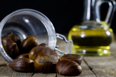 Tasty edible chestnuts on a wooden kitchen table. Chestnuts in the kitchen on a gray wooden kitchen table. Black background.の写真素材