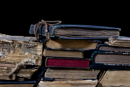 Old destroyed books on a wooden table. Reading room library with very old books on a wooden table. Black background.の写真素材