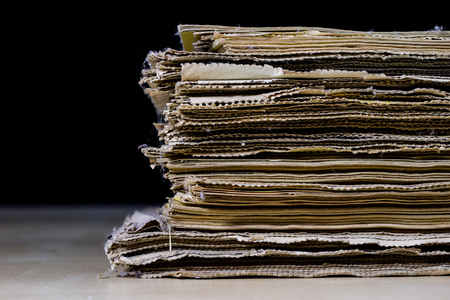 The spines of old books lying on the stack. Books stacked on an old table. Black background.
