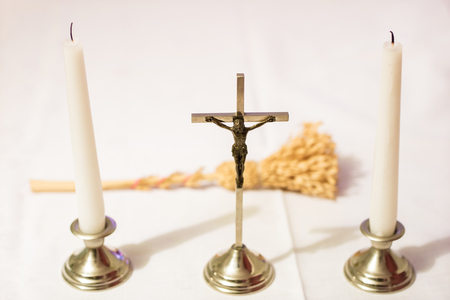 Cross and candles on a white tablecloth. Carol singing, cross and candles on a white table. Holiday time.の写真素材