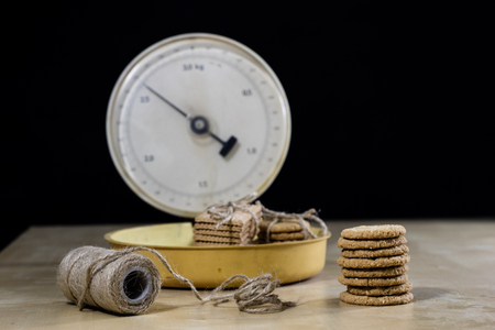 Samoyed cakes tied in bundles and kitchen scale. Cookies on a wooden kitchen table. Black background.の写真素材