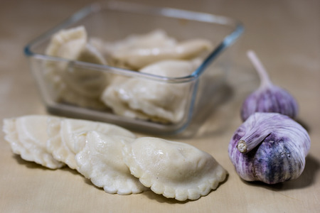 Tasty dumplings arranged on a light wooden kitchen table. Dumplings bowl and oil in the kitchen. Kitchen atmosphere.の写真素材