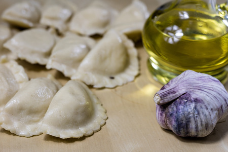 Tasty dumplings arranged on a light wooden kitchen table. Dumplings bowl and oil in the kitchen. Kitchen atmosphere.の写真素材
