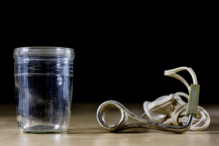 Heating water in a glass after mustard. The old method of brewing tea. Black background.の写真素材