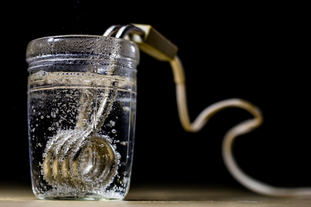 Heating water in a glass after mustard. The old method of brewing tea. Black background.の写真素材