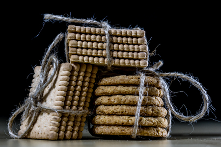Cookies tied with a gray jute string into a bow. Cookies of sweets on a wooden kitchen table. Black background.の写真素材
