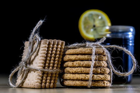 Cookies tied with a gray jute string into a bow. Cookies of sweets on a wooden kitchen table. Black background.の写真素材