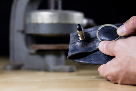 Repairing a bicycle tube in a tire bonding workshop. Detek repair station in the vulcanization workshop. Black background.の写真素材