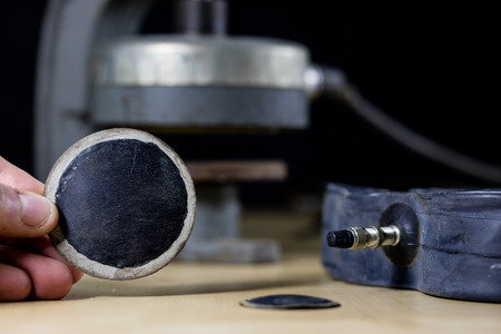 Repairing a bicycle tube in a tire bonding workshop. Detek repair station in the vulcanization workshop. Black background.の写真素材