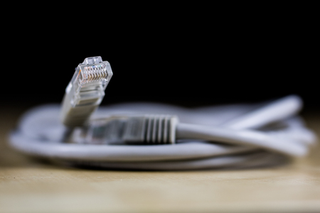 Electric cables, plugs and connectors on a wooden workshop table. Accessories and electrical components. Black background.の写真素材