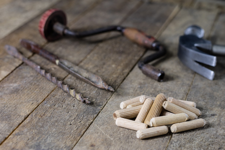 Joinery tools in a workshop. Drill, hammer and other tools on a wooden workshop table. Black background.の写真素材