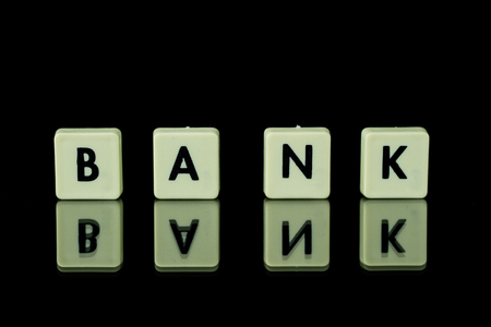 blocks with letters set on a glass table. Words arranged from letters on a glass substrate. The words bank,  A black backgroundの写真素材