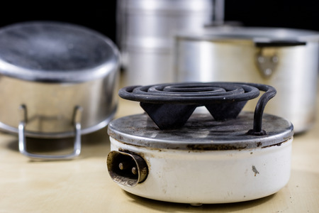 Electric razor for cooking lunch and water for tea. Old kitchen accessories on an old heater. Black background.の写真素材