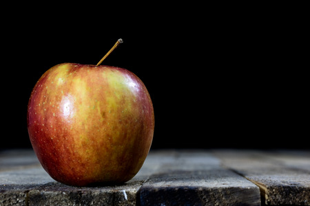 Big red apples in a dark wooden box. Wooden crate and apples on a wooden table in the kitchen. Black background.の写真素材