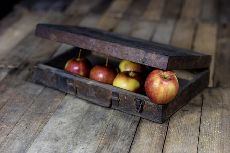 Big red apples in a dark wooden box. Wooden crate and apples on a wooden table in the kitchen. Black background.の写真素材