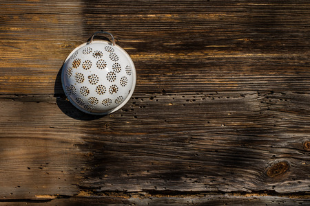 Old house and wooden walls with a colander. Kitchen accessories on the old wall of a wooden house. Season of the spring.の写真素材